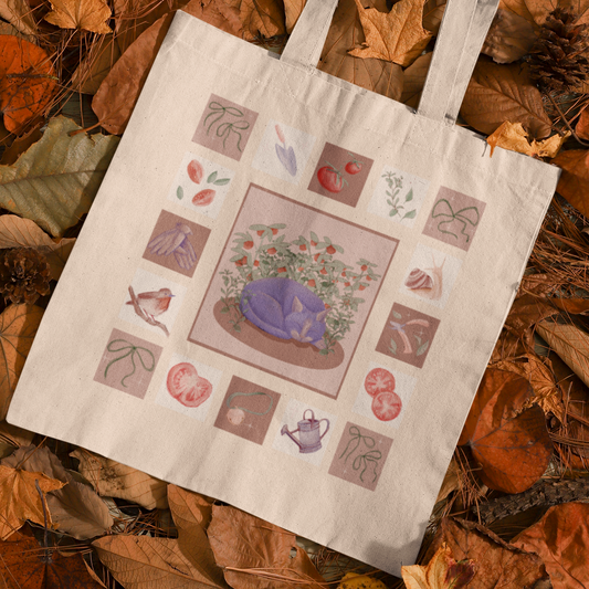 Tote bag with a purple cat illustration on a bed of autumn leaves